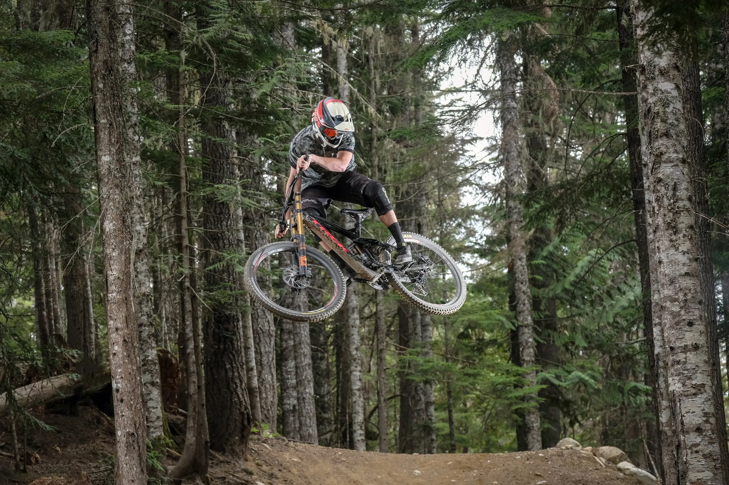 Rowerzysta enduro w skoku na leśnej trasie